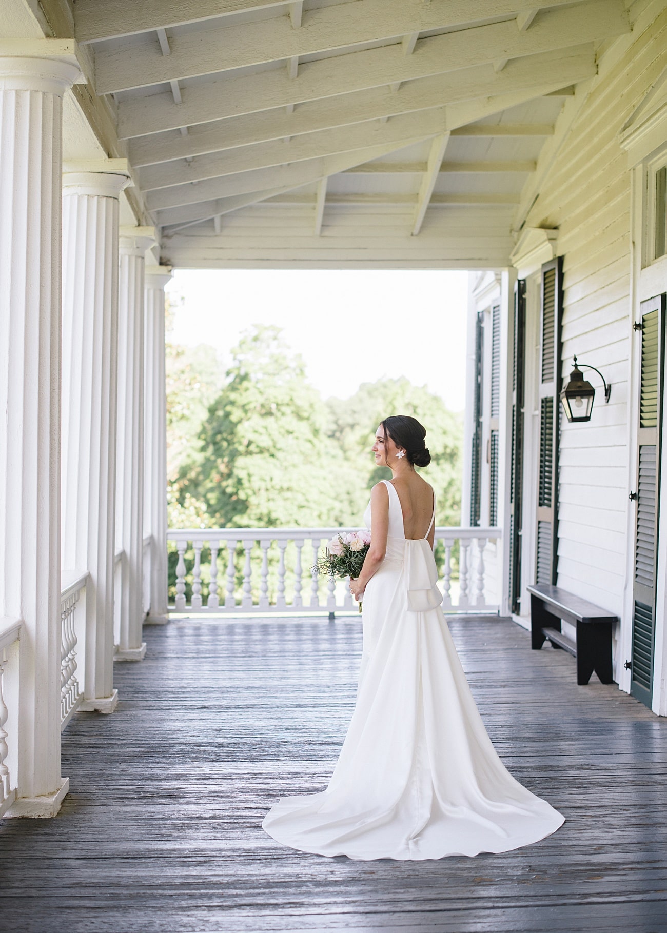 Bride posing on southern mansion porch at Redcliffe Plantation in Aiken, South Carolina